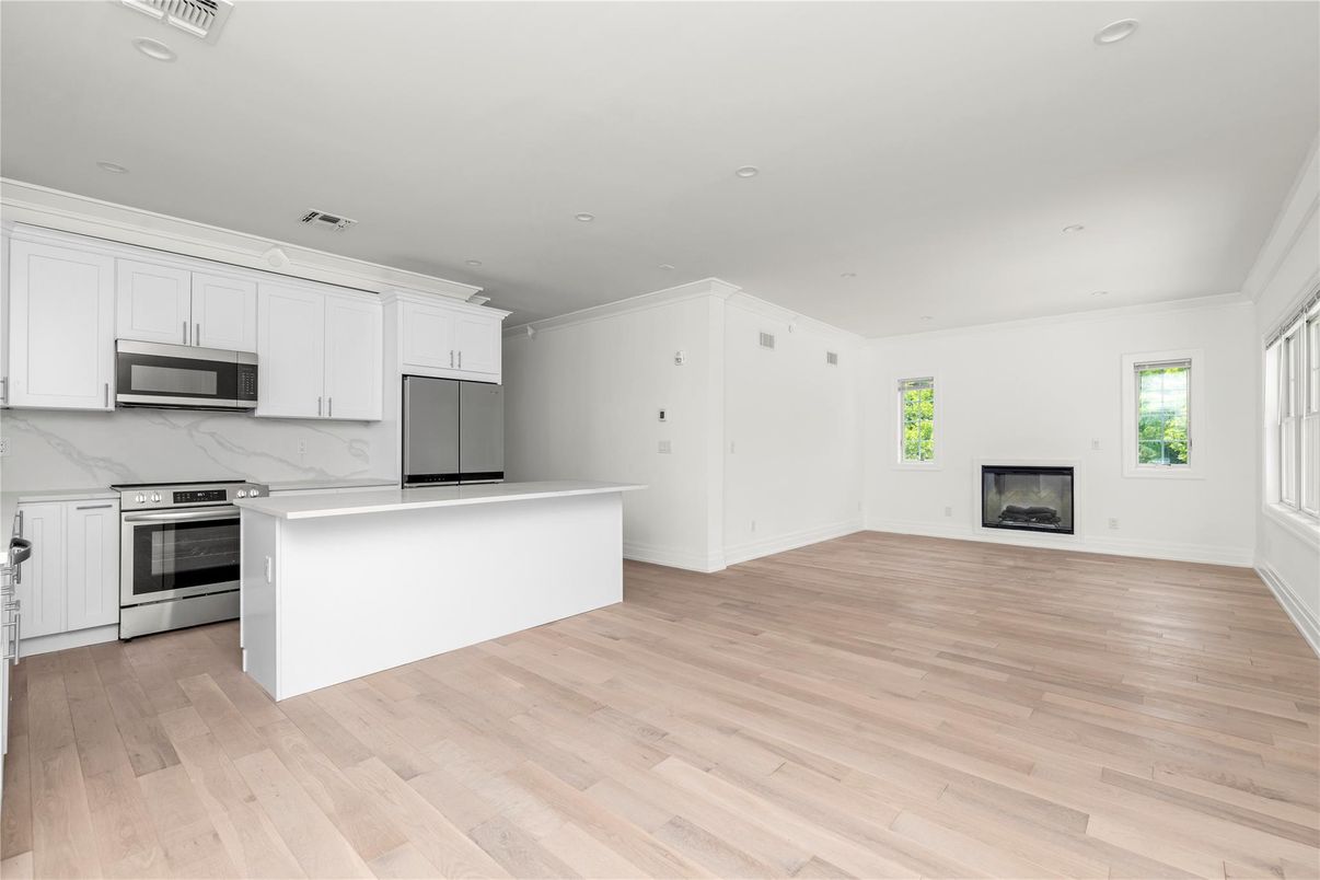 Empty room, Fireplace, Interior, Kitchen, Marble Walls, Recessed Lighting, Stainless Steel Appliances, Wood Texture Flooring