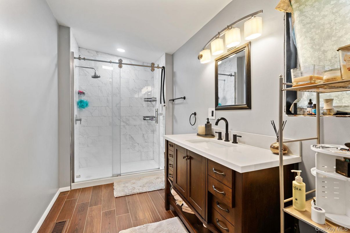 Bathroom, Dual Sink Vanities, Glass Shower, Interior, Marble Walls, Recessed Lighting, Wood Texture Flooring