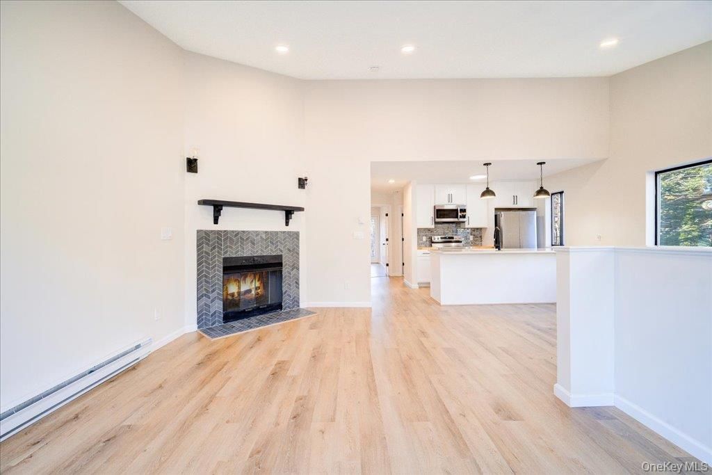 Empty room, Fireplace, Interior, Kitchen, Pendant Lights, Recessed Lighting, Stainless Steel Appliances, Wood Texture Flooring