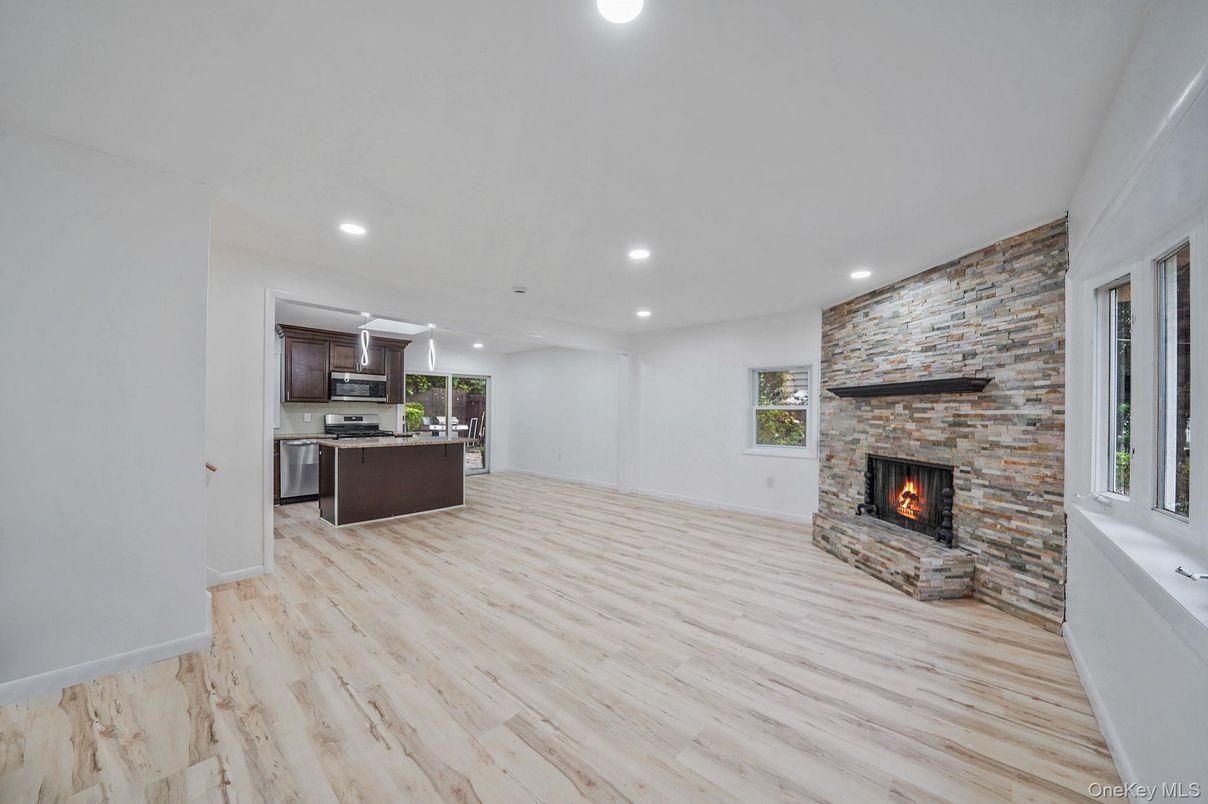 Empty room, Fireplace, Interior, Kitchen, Recessed Lighting, Stainless Steel Appliances, Stone Walls, Wood Texture Flooring