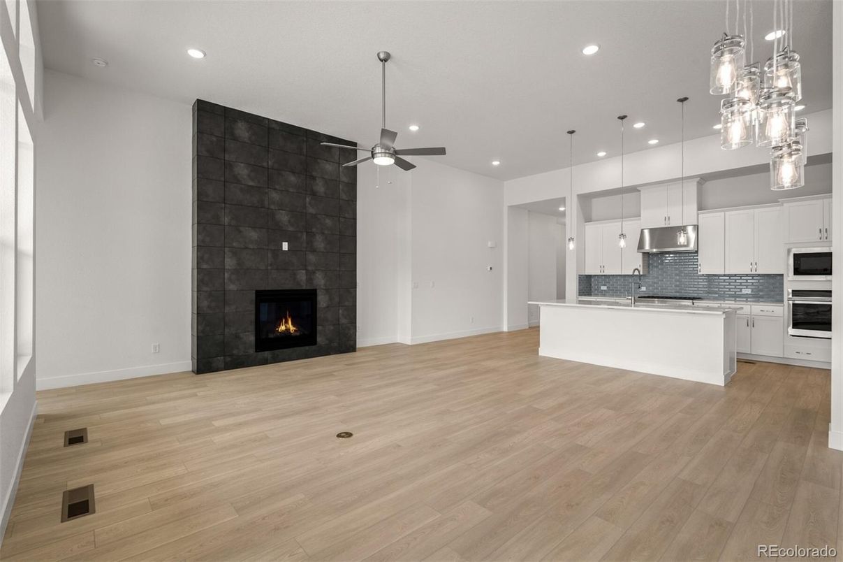 Empty room, Fireplace, Interior, Kitchen, Pendant Lights, Recessed Lighting, Stainless Steel Appliances, Wood Texture Flooring
