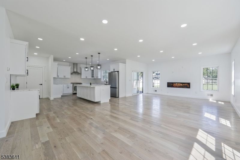 Empty room, Fireplace, Interior, Kitchen, Pendant Lights, Recessed Lighting, Stainless Steel Appliances, Wood Texture Flooring