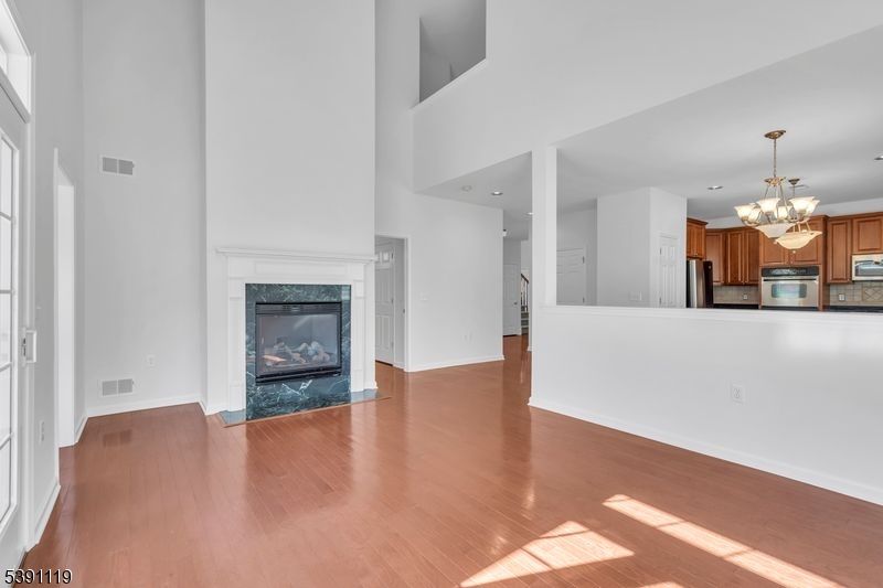 Chandelier, Empty room, Fireplace, Interior, Kitchen, Recessed Lighting, Stainless Steel Appliances, Wood Texture Flooring