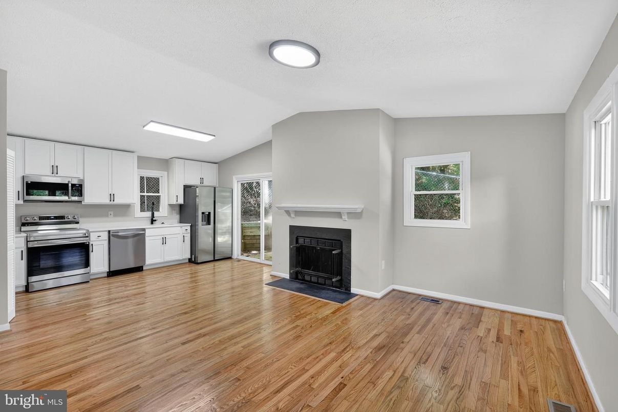 Empty room, Fireplace, Interior, Kitchen, Recessed Lighting, Stainless Steel Appliances, Wood Texture Flooring