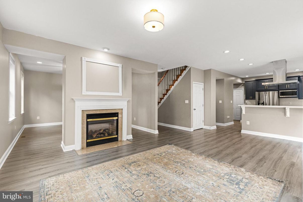 Empty room, Fireplace, Interior, Kitchen, Recessed Lighting, Stainless Steel Appliances, Wood Texture Flooring