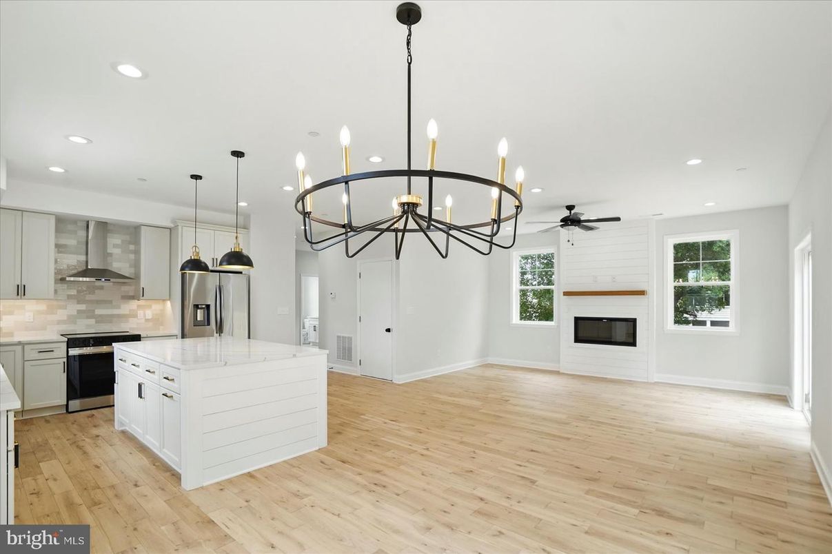 Chandelier, Empty room, Fireplace, Interior, Kitchen, Pendant Lights, Recessed Lighting, Stainless Steel Appliances, Wood Texture Flooring