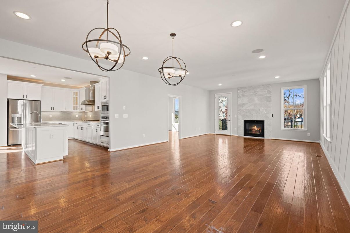 Chandelier, Empty room, Fireplace, Interior, Kitchen, Pendant Lights, Recessed Lighting, Stainless Steel Appliances, Wood Texture Flooring