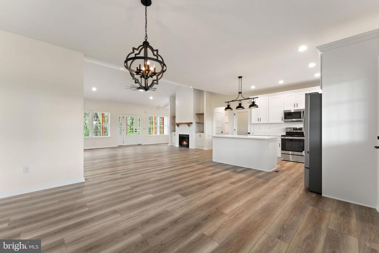 Chandelier, Empty room, Fireplace, Interior, Kitchen, Pendant Lights, Recessed Lighting, Stainless Steel Appliances, Wood Texture Flooring