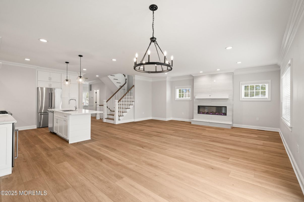 Chandelier, Empty room, Fireplace, Interior, Kitchen, Pendant Lights, Recessed Lighting, Stainless Steel Appliances, Wood Texture Flooring