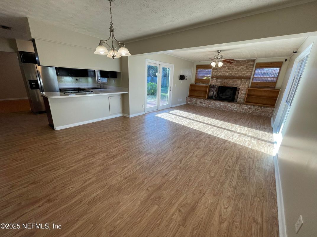 Empty room, Fireplace, Interior, Kitchen, Pendant Lights, Stainless Steel Appliances, Wood Texture Flooring
