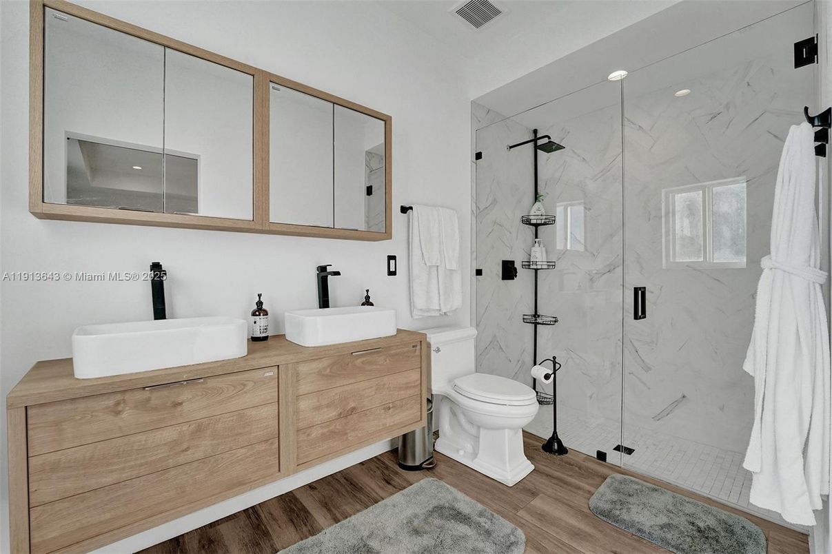 Bathroom, Dual Sink Vanities, Glass Shower, Interior, Marble Walls, Recessed Lighting, Wood Texture Flooring