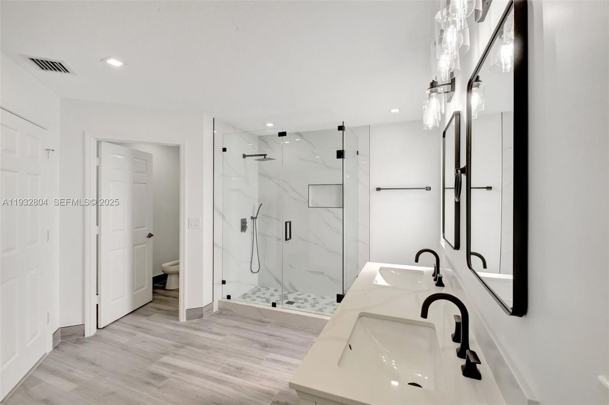 Bathroom, Dual Sink Vanities, Glass Shower, Interior, Marble Walls, Recessed Lighting, Wood Texture Flooring