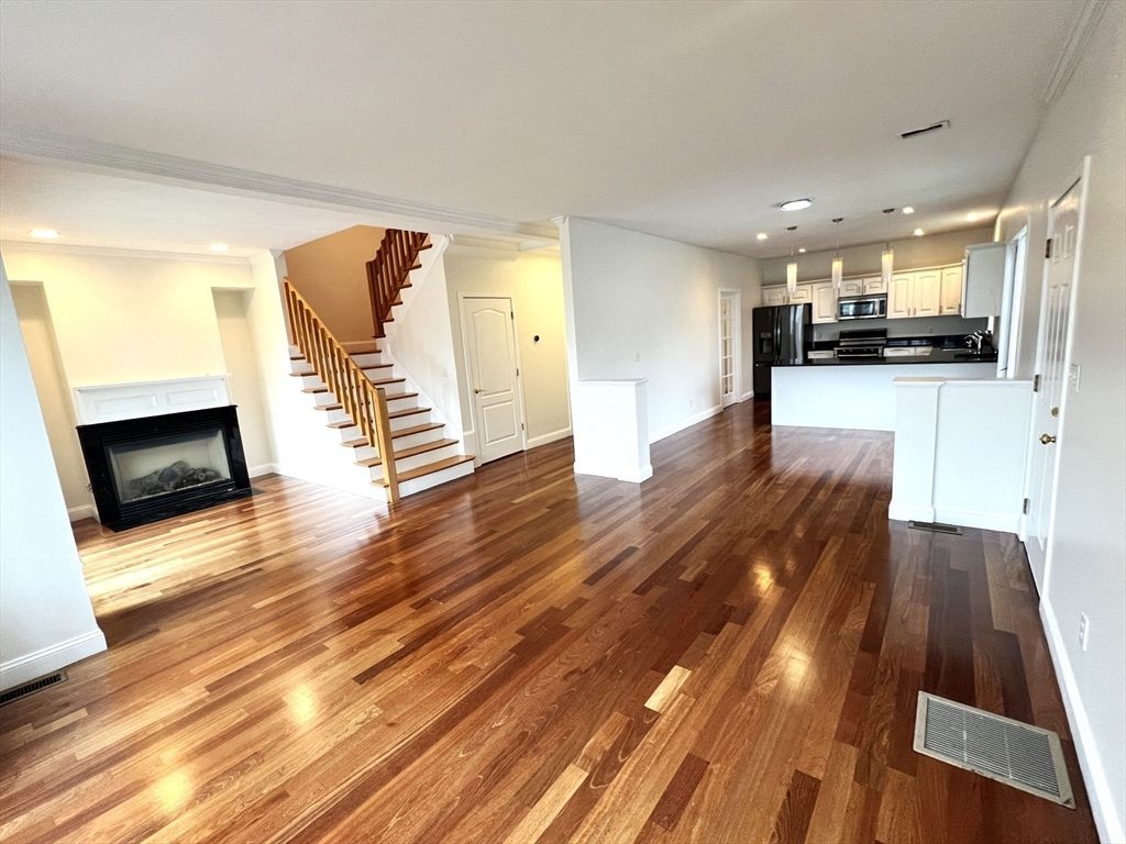 Empty room, Fireplace, Interior, Kitchen, Pendant Lights, Recessed Lighting, Stainless Steel Appliances, Wood Texture Flooring