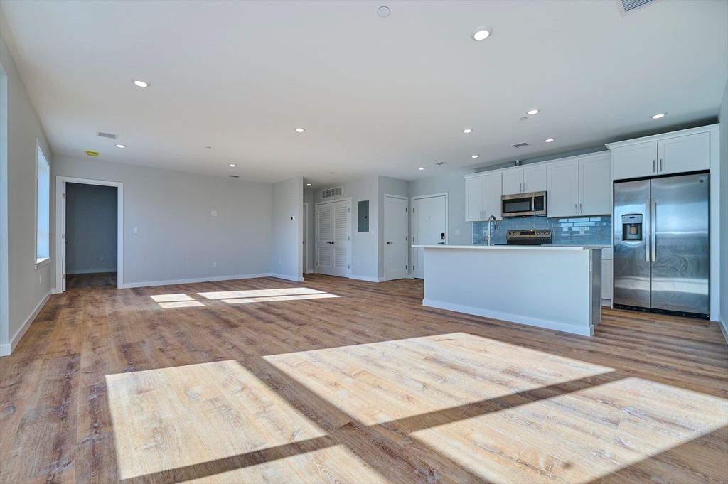 Empty room, Interior, Kitchen, Recessed Lighting, Stainless Steel Appliances, Wood Texture Flooring