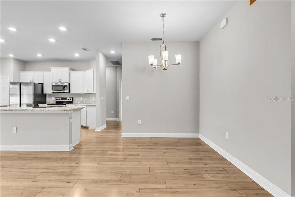 Chandelier, Empty room, Interior, Kitchen, Pendant Lights, Recessed Lighting, Stainless Steel Appliances, Wood Texture Flooring