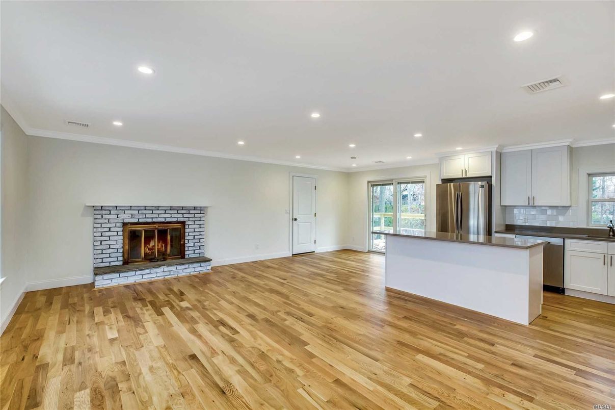 Empty room, Fireplace, Interior, Kitchen, Recessed Lighting, Stainless Steel Appliances, Wood Texture Flooring