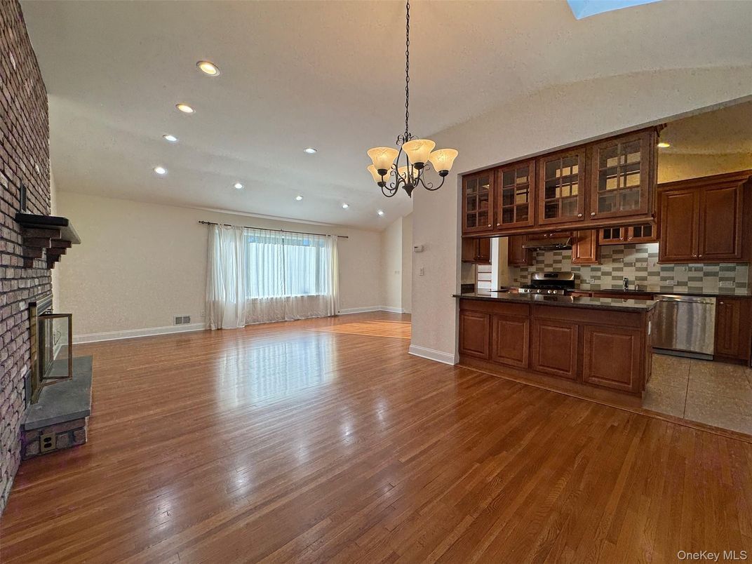Chandelier, Empty room, Fireplace, Interior, Kitchen, Recessed Lighting, Stainless Steel Appliances, Wood Texture Flooring