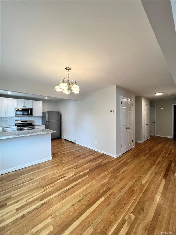 Empty room, Interior, Kitchen, Recessed Lighting, Stainless Steel Appliances, Wood Texture Flooring