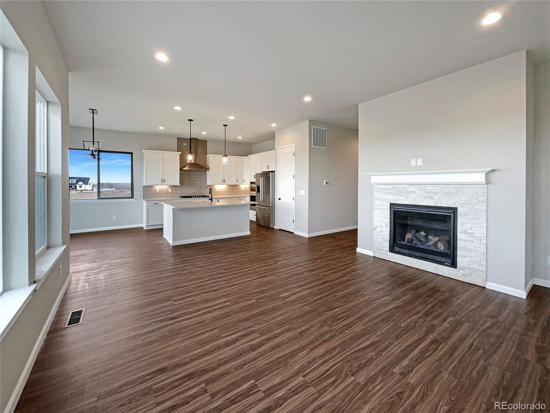 Empty room, Fireplace, Interior, Kitchen, Pendant Lights, Recessed Lighting, Stainless Steel Appliances, Wood Texture Flooring