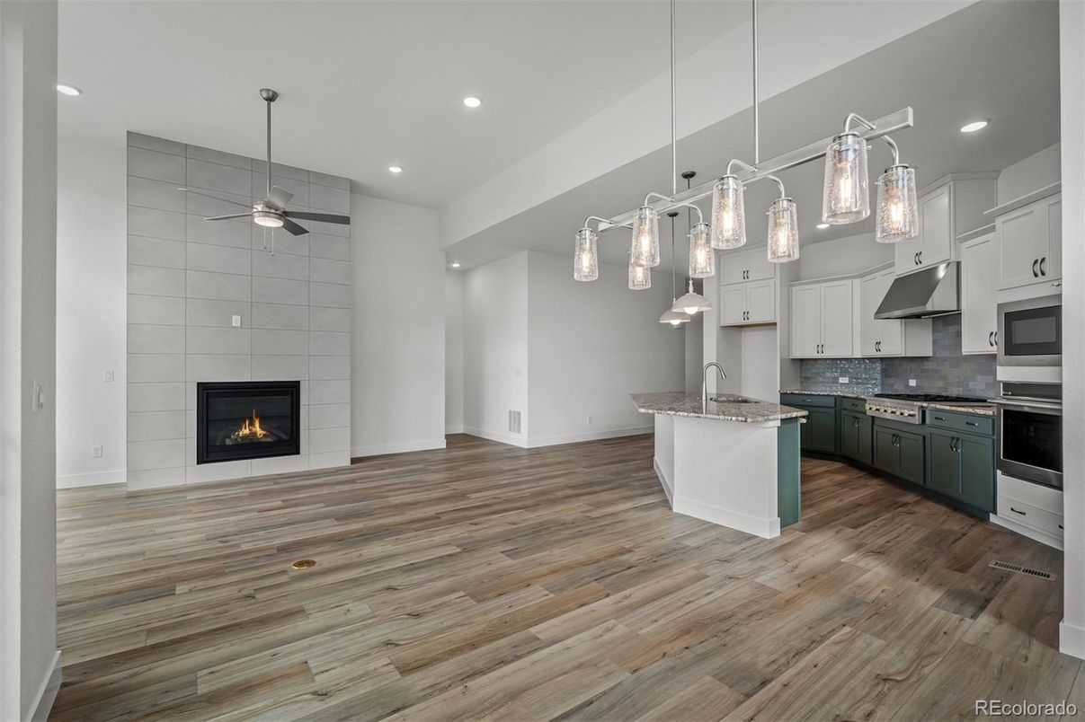 Empty room, Fireplace, Interior, Kitchen, Pendant Lights, Recessed Lighting, Stainless Steel Appliances, Wood Texture Flooring