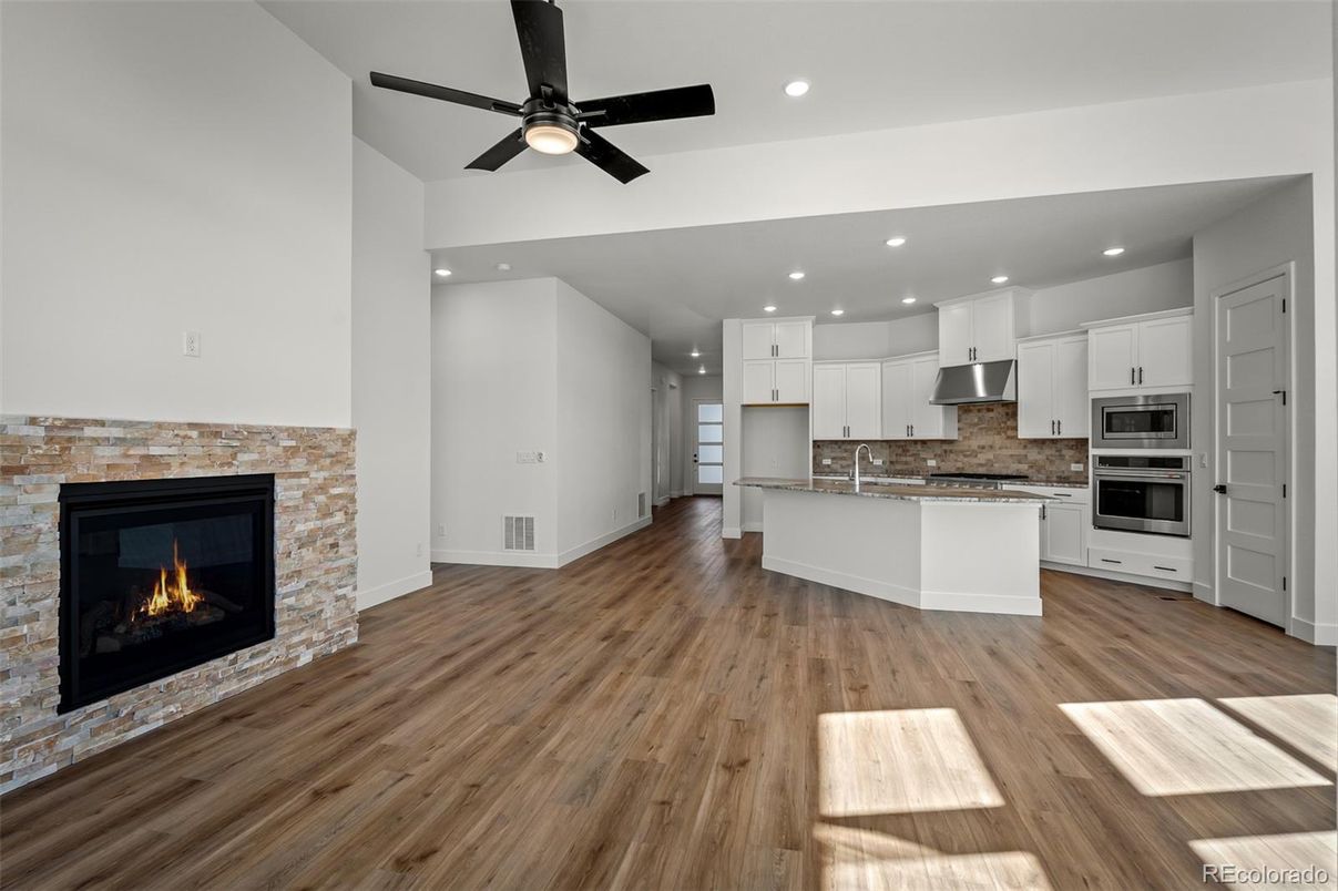 Empty room, Fireplace, Interior, Kitchen, Recessed Lighting, Stainless Steel Appliances, Wood Texture Flooring