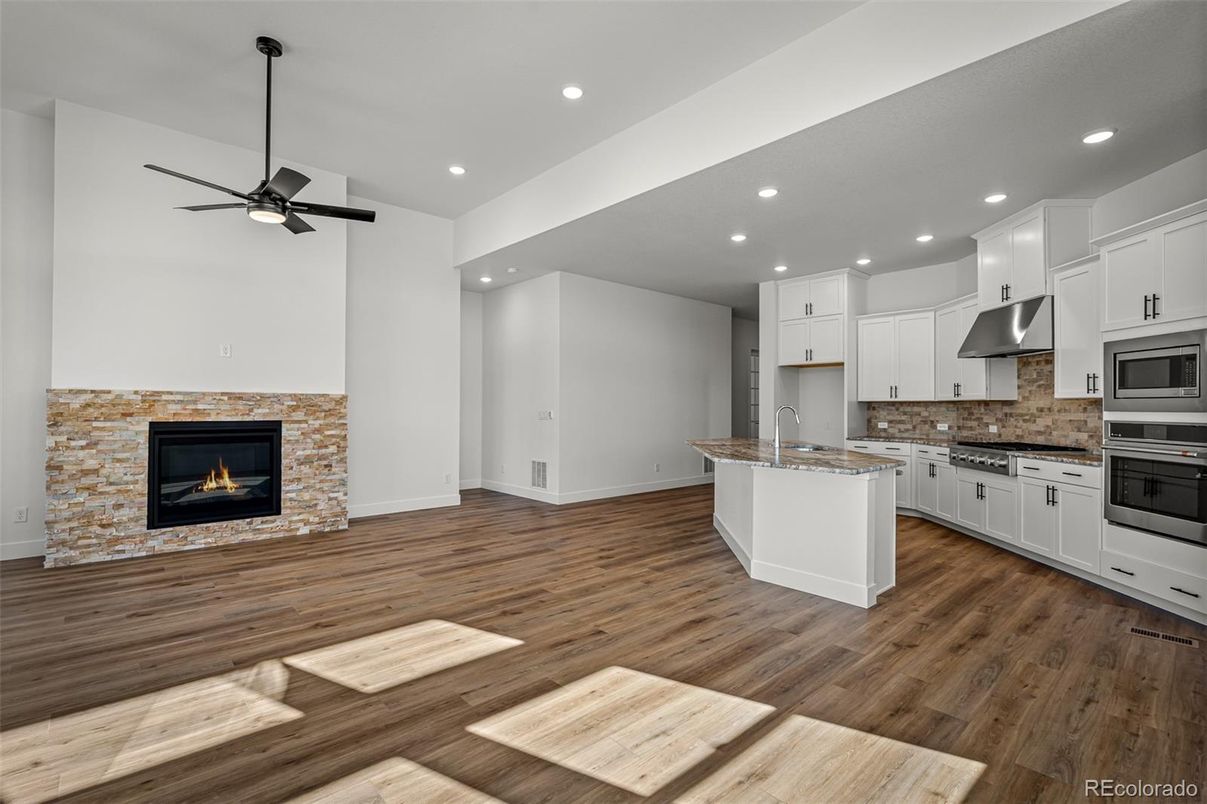 Empty room, Fireplace, Interior, Kitchen, Recessed Lighting, Stainless Steel Appliances, Wood Texture Flooring