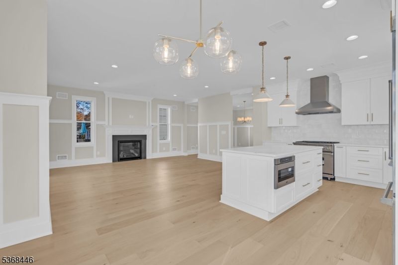 Empty room, Fireplace, Interior, Kitchen, Pendant Lights, Recessed Lighting, Stainless Steel Appliances, Wood Texture Flooring